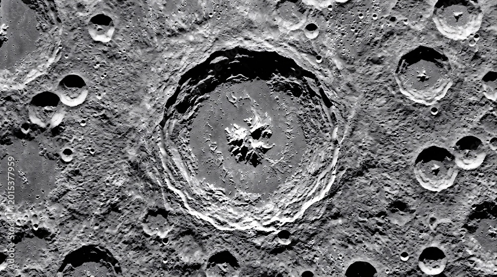 Fototapeta premium Detailed overhead view of lunar impact crater with complex central ridge and textured ejecta patterns across the moon surface in sharp black and white detail.