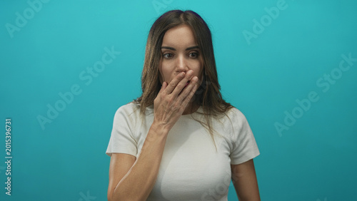 Foto Young hispanic woman with a shocked expression finger to lips for silence in a turquoise studio; surprise