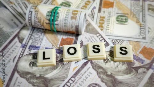 Tableau sur toile The word LOSS spelled in tile blocks rests atop a spread of United States hundred-dollar bills, illustrating a negative financial outcome, deficit, or investment setback in a monetary context