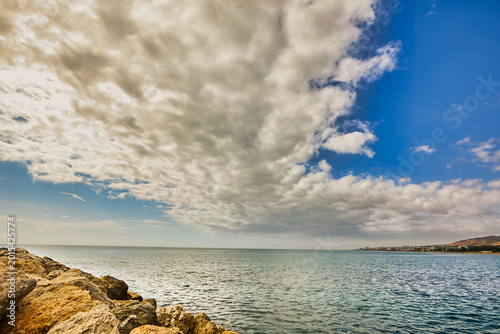 Coastal rocks meeting the sea under summer clouds