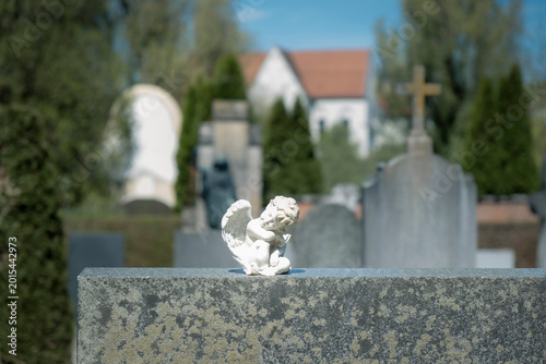 Small angel figurine on cemetery grave stone