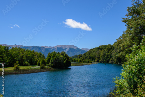 Tableau sur toile Hermosa vista del río Manso conectando lagos Hess, rodeado de frondosos bosques nativos y la cordillera de fondo bajo un cielo azul, Patagonia, Argentina