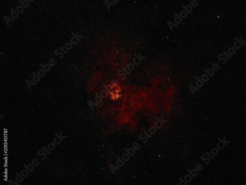 фотографія Glowing red nebula, composed of vast clouds of gas and dust, shines against a dense background of countless distant stars