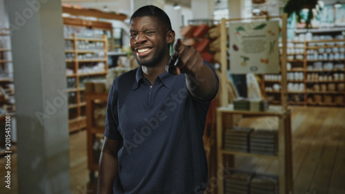 Schilderij op canvas Man points finger at camera showing his hand and smile in a building, close and direct gesture of invitation; friendly joyful welcome