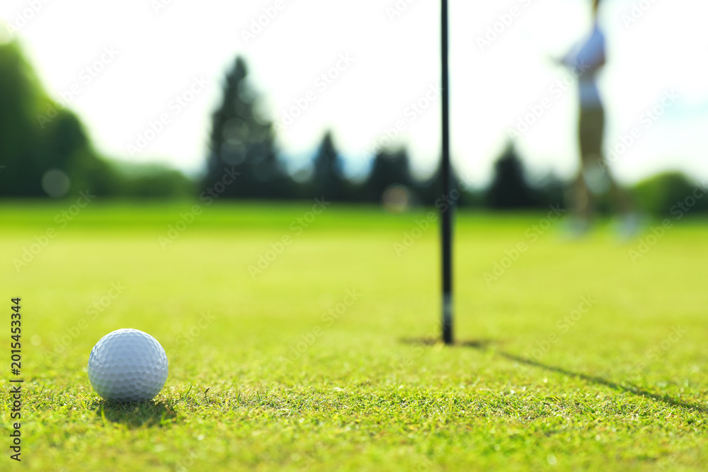 Obraz premium Woman playing golf at green course, focus on ball. Space for text