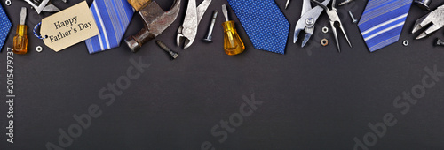 Happy Fathers Day gift tag with top border of ties and tools on a black paper banner background. Overhead view with copy space.