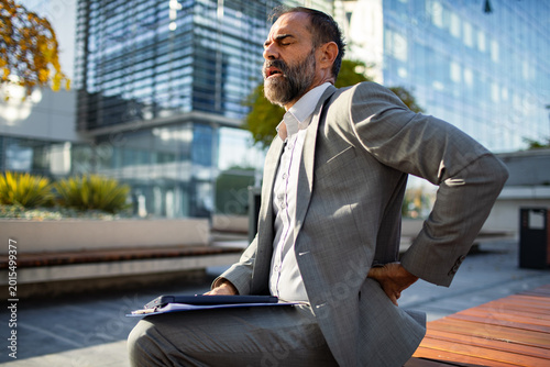 Businessman with lower back pain outdoors in city