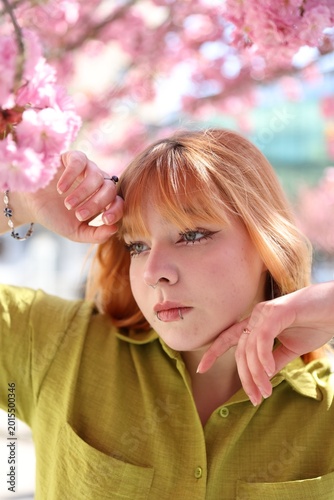 Foto Beautiful young girl posing near blossoming sakura tree outdoors