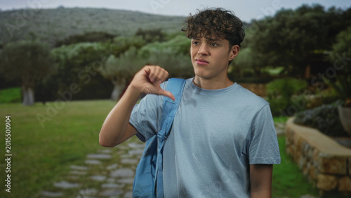 Εκτύπωση καμβά Man with backpack shows thumbs down gesture on forest path, also pointing in other frames; disapproval reluctance
