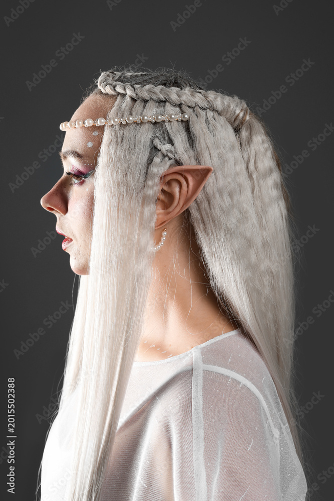 Fototapeta premium Beautiful girl dressed as elf on grey background