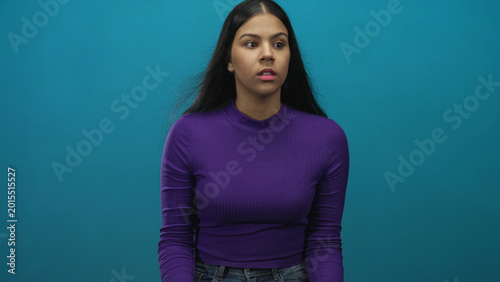 Schilderij op canvas Woman clenching fists and looking off camera with focused gaze in studio with teal background; determination empowerment confidence focus