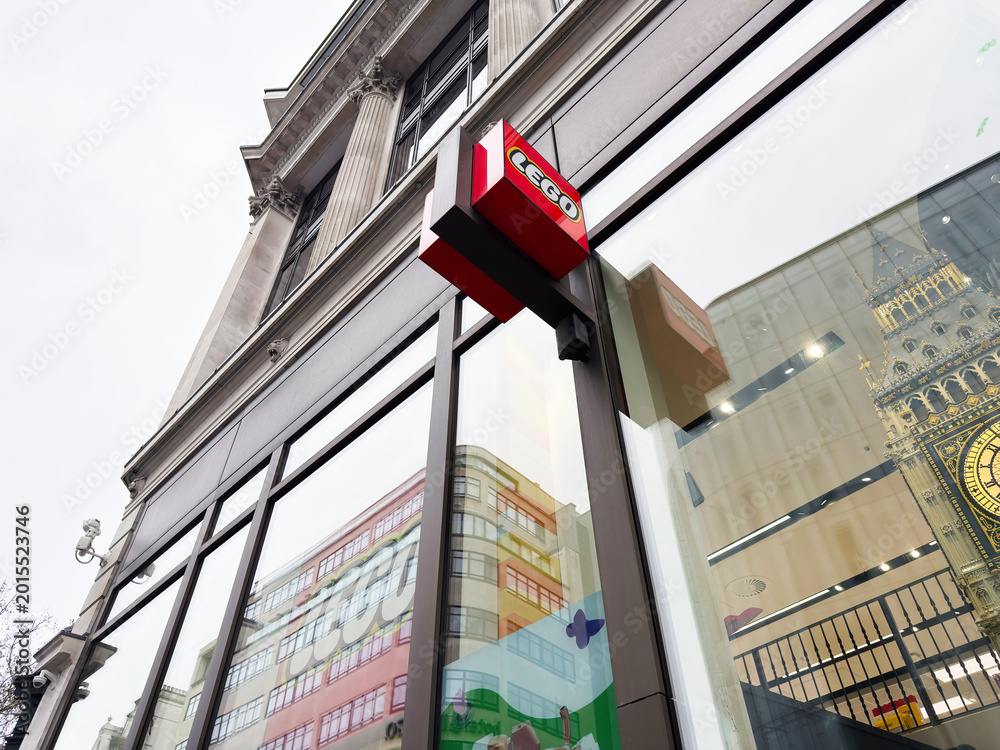 Fototapeta premium Lego store facade with glass reflections and Big Ben detail in central London, UK, showing modern retail architecture and iconic city landmark in window reflection