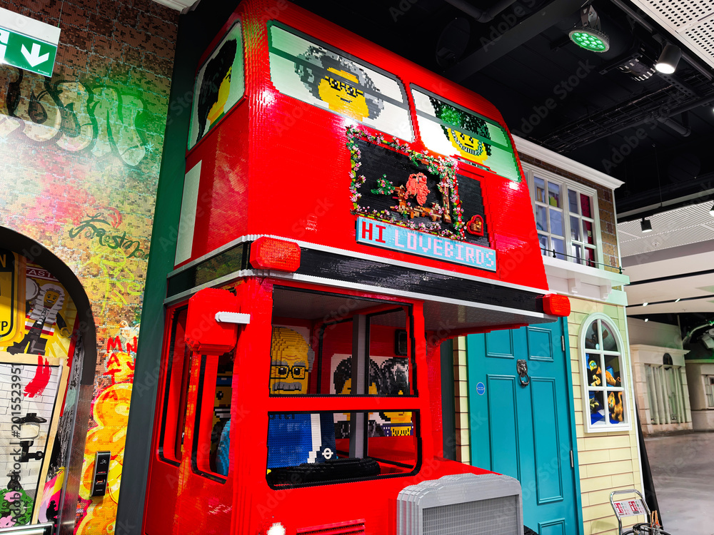 Fototapeta premium Red Lego double decker bus display with smiling minifigure faces in a colorful London UK toy store scene