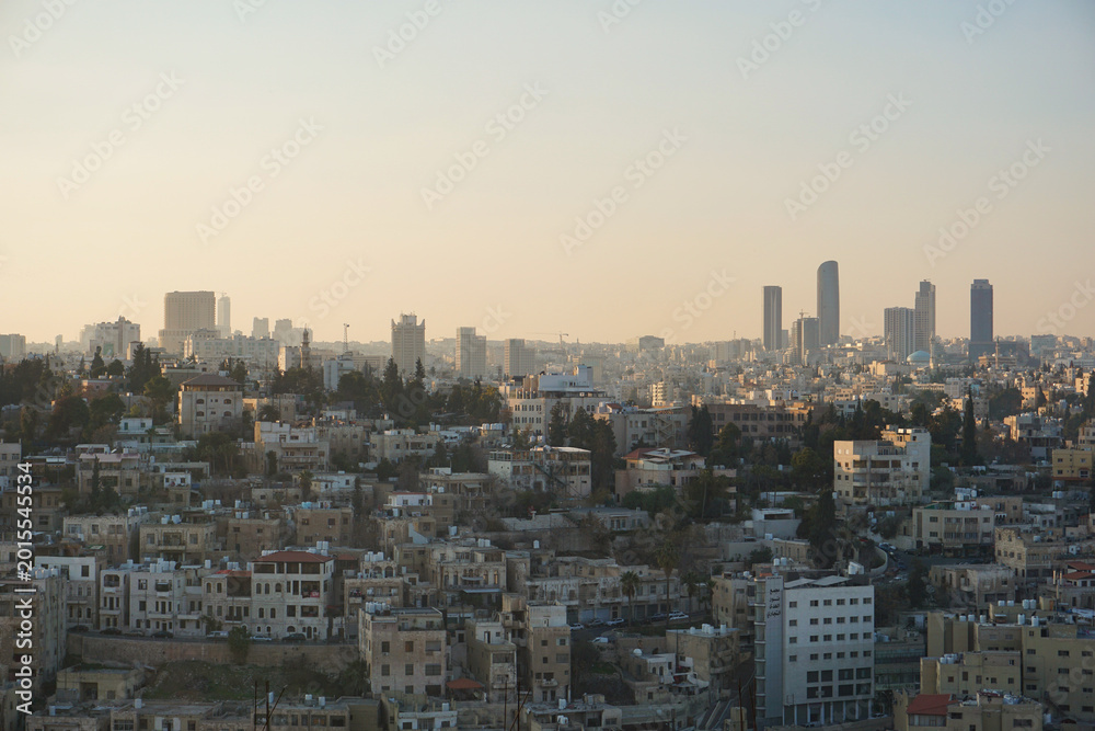 Obraz premium Panoramic skyline of Amman, Jordan, during a colorful sunset with warm golden light illuminating the city