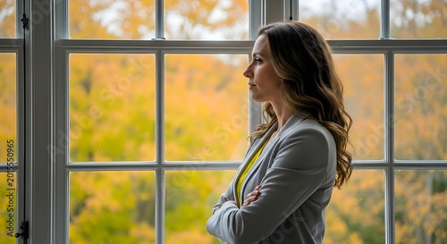 Thoughtful contemplation through the window, a woman pauses to connect with the autumnal landscape, reflecting on the cyclical nature of seasons and environmental change.