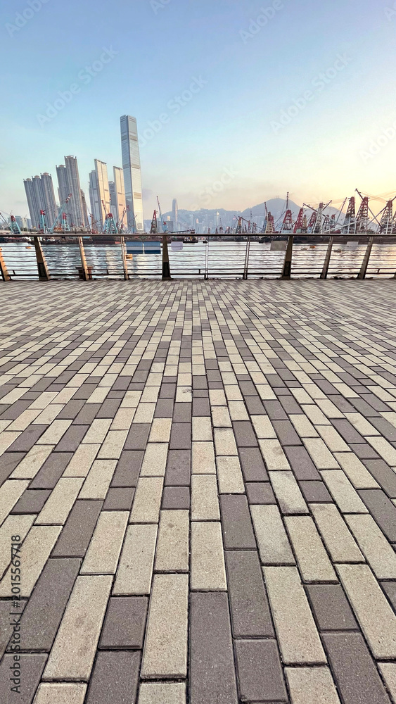 Fototapeta premium Hong Kong skyline with construction cranes and waterfront promenade at sunrise