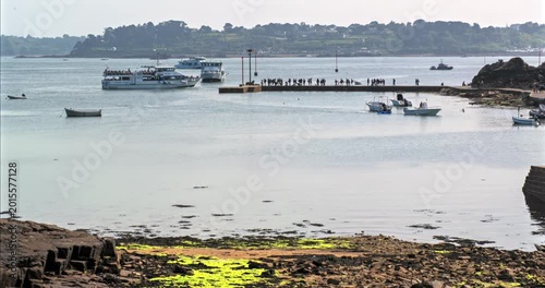 Timelapse showing harbor and boat activity on Brehat Island in Brittany, France. Coastal landscape with marina, tourists and calm atmosphere of the French coastline during sunny day.