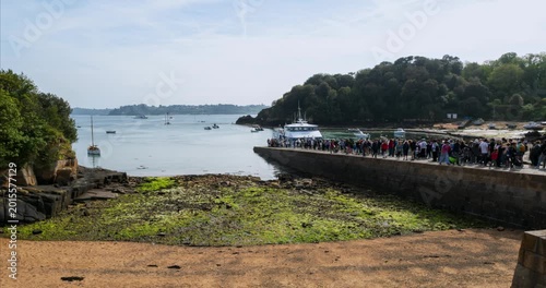 Timelapse showing tourists moving around the harbor on Brehat Island in Brittany, France. Coastal landscape with boats, marina activity and sunny weather - Camera moving forward