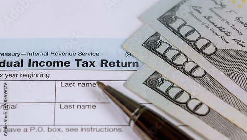 Tax return form with pen and cash on top for payment