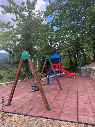 Colorful playground with swings and slide surrounded by trees in nature