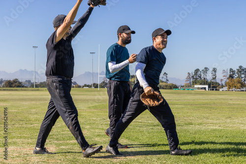 Photography Vertical video: Sun encouraging three teammates walking across field, holding ba