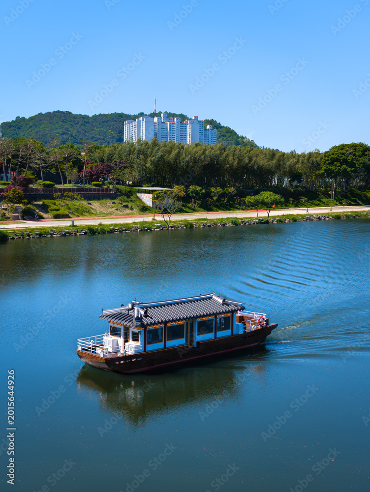 Fototapeta premium Jinju City spring landscape in Jinju Namgang River with Hanok traditional house style cruise ship and Cheonsugyo bridge in Gyeongsangnam‑do, South Korea
