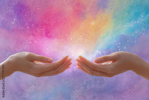 Two hands reaching together against colorful rainbow watercolor background with sparkles. Connection, unity and spiritual concept art.