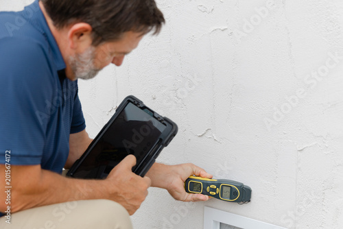 Fotografi An environmental home inspector is viewed close-up at work, using an electronic moisture meter to detect signs of damp and rot in structural elements