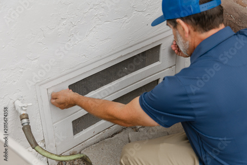 Cuadro en lienzo A home inspector is opening a crawl space access hatch underneath a residential