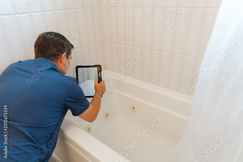 Foto Home inspector inspecting bath tub tiles