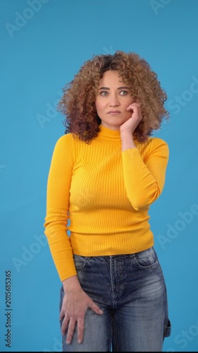 Woman in yellow sweater showing negative emotions from bad ideas  in front of blue background  