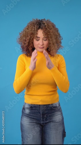 Woman showing negative emotions blue background and yellow sweater during a studio shoot in the afternoon