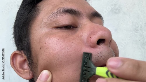 Close up of a man shaving his mustache with a manual razor