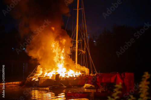Fotografija Burning sailboat floating on the water at night with large orange flames