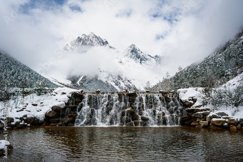 Fotografie Snow-Covered Waterfall with Twin Mountain Peaks at Bipenggou Valley, Sichuan, Ch