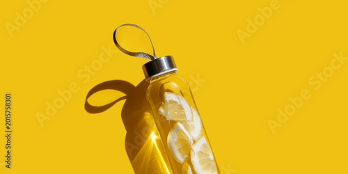 Obraz na plátne Lemon fruit water drink detox in bottle on yellow shadow at sunlight, banner
