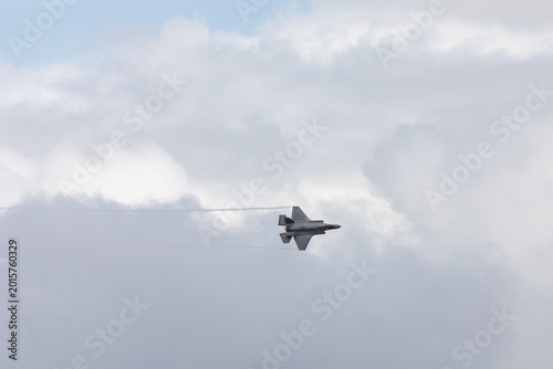 American 5th generation stealth fighter jet of the US Air Force performing aerial maneuvers in cloudy skies. Powerful modern military aircraft flying during aviation demonstration