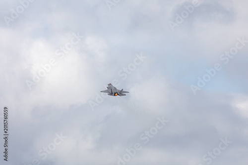 American 5th generation stealth fighter jet of the US Air Force performing aerial maneuvers in cloudy skies. Powerful modern military aircraft flying during aviation demonstration