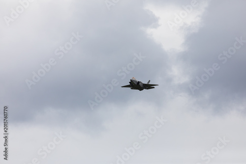 American 5th generation stealth fighter jet of the US Air Force performing aerial maneuvers in cloudy skies. Powerful modern military aircraft flying during aviation demonstration