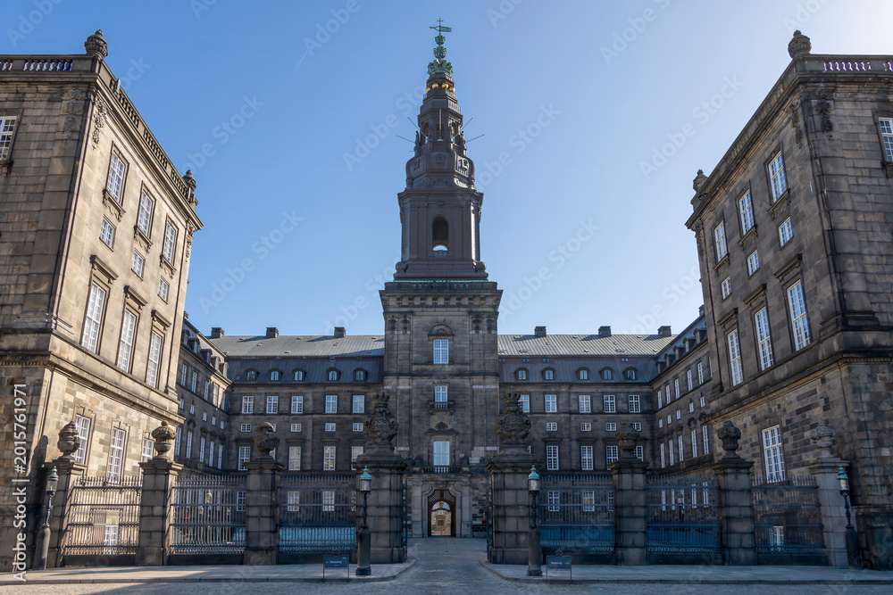 Obraz premium A majestic view of Christiansborg Palace in Copenhagen, showcasing its grand architecture against a clear blue sky.