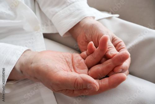 фотографія A senior woman's hand touching her finger joints.