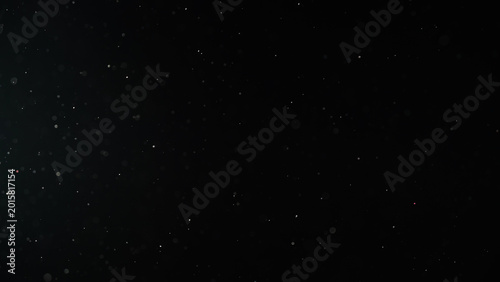 Slow motion real dust particles floating mid air over dark background