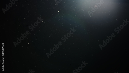 Slow motion real dust particles floating mid air over dark background
