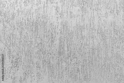 Texture of grey decorative plaster with a vertical scratched pattern on a building wall facade finish.