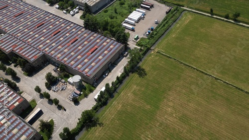 Industrial Landscape: Aerial view of a large industrial complex, featuring vast warehouses, parking areas, and adjacent fields, showcasing the scale of modern infrastructure and industrial activity.