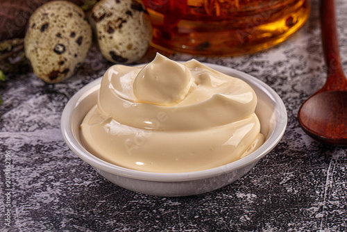 Canvas Print Creamy mayonnaise in bowl with quail eggs, herbs and wooden spoon