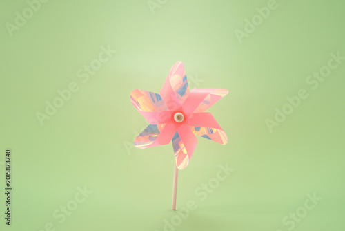 Fotografie Pink holographic pinwheel bird deterrent on green background humane pest control