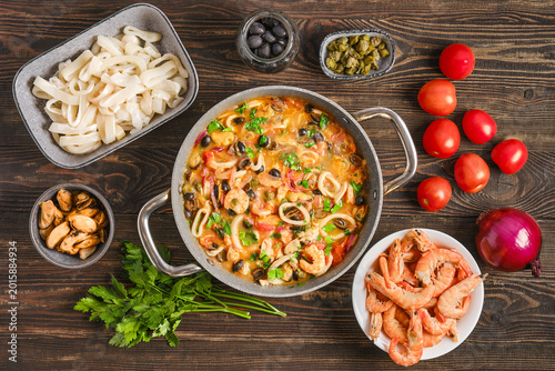 Bild auf Leinwand Seafood saute with tomatoes and black olives with fresh ingredients on wooden ta