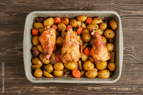 Roasting rabbit and vegetables in a dish on a wooden table for a family meal
