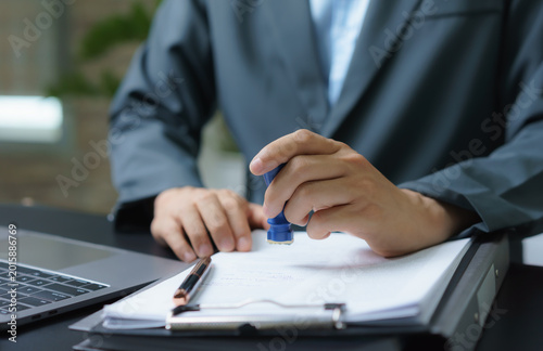 Businessman stamping approval on legal document with official seal, business contract authorization, paper verification and corporate compliance concept.
